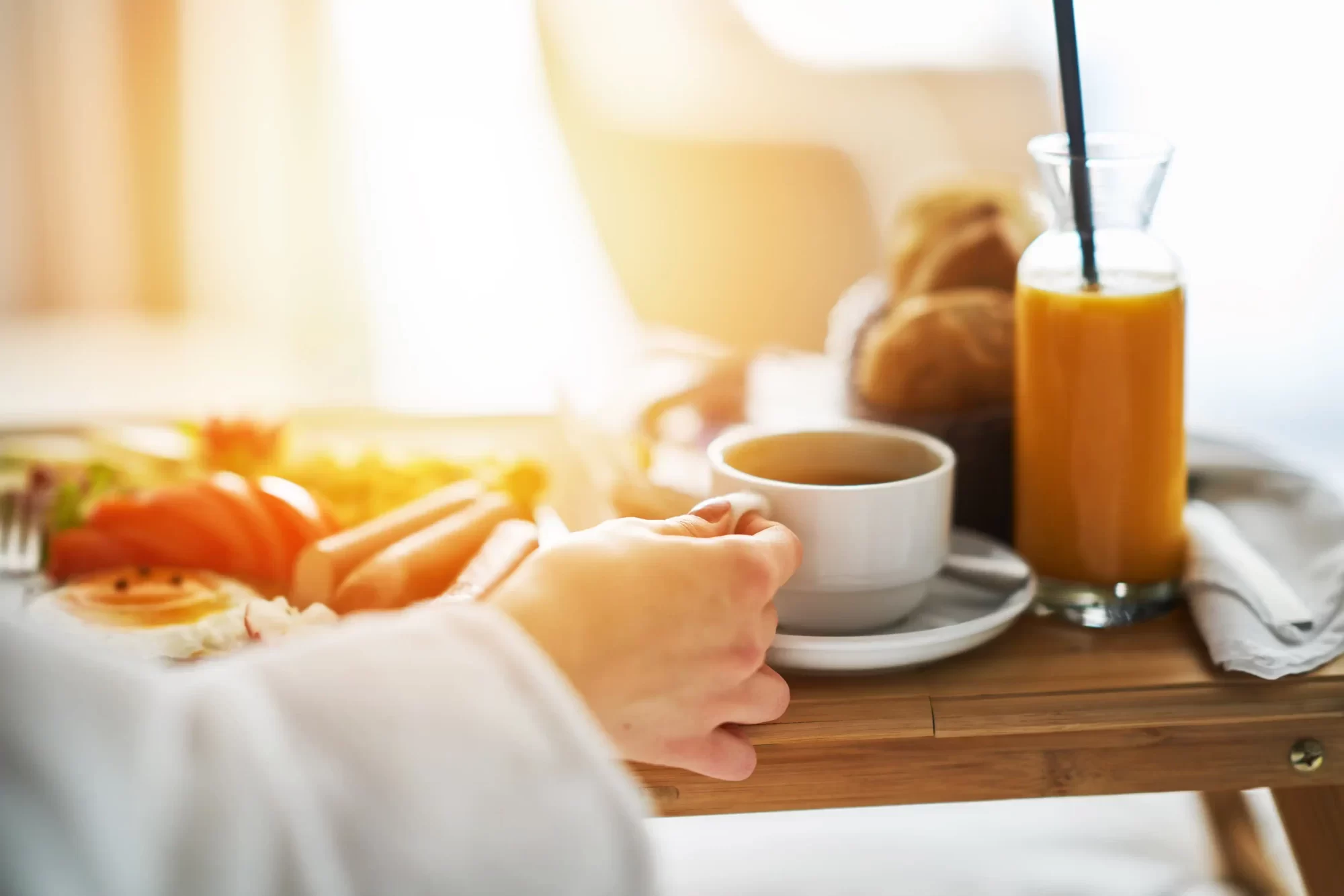Colazione a letto con succo d'arancia e tè su un vassoio.