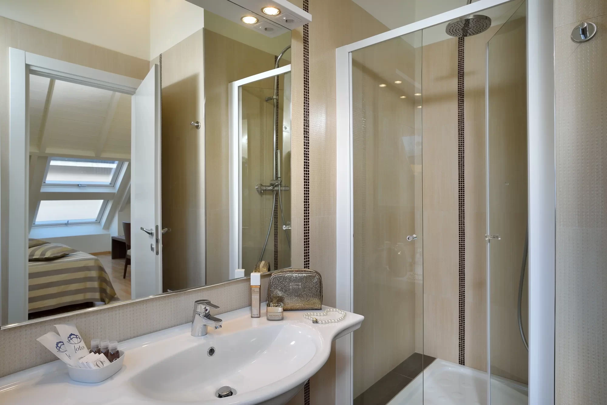 Bagno moderno con cabina doccia in vetro e lavandino bianco.