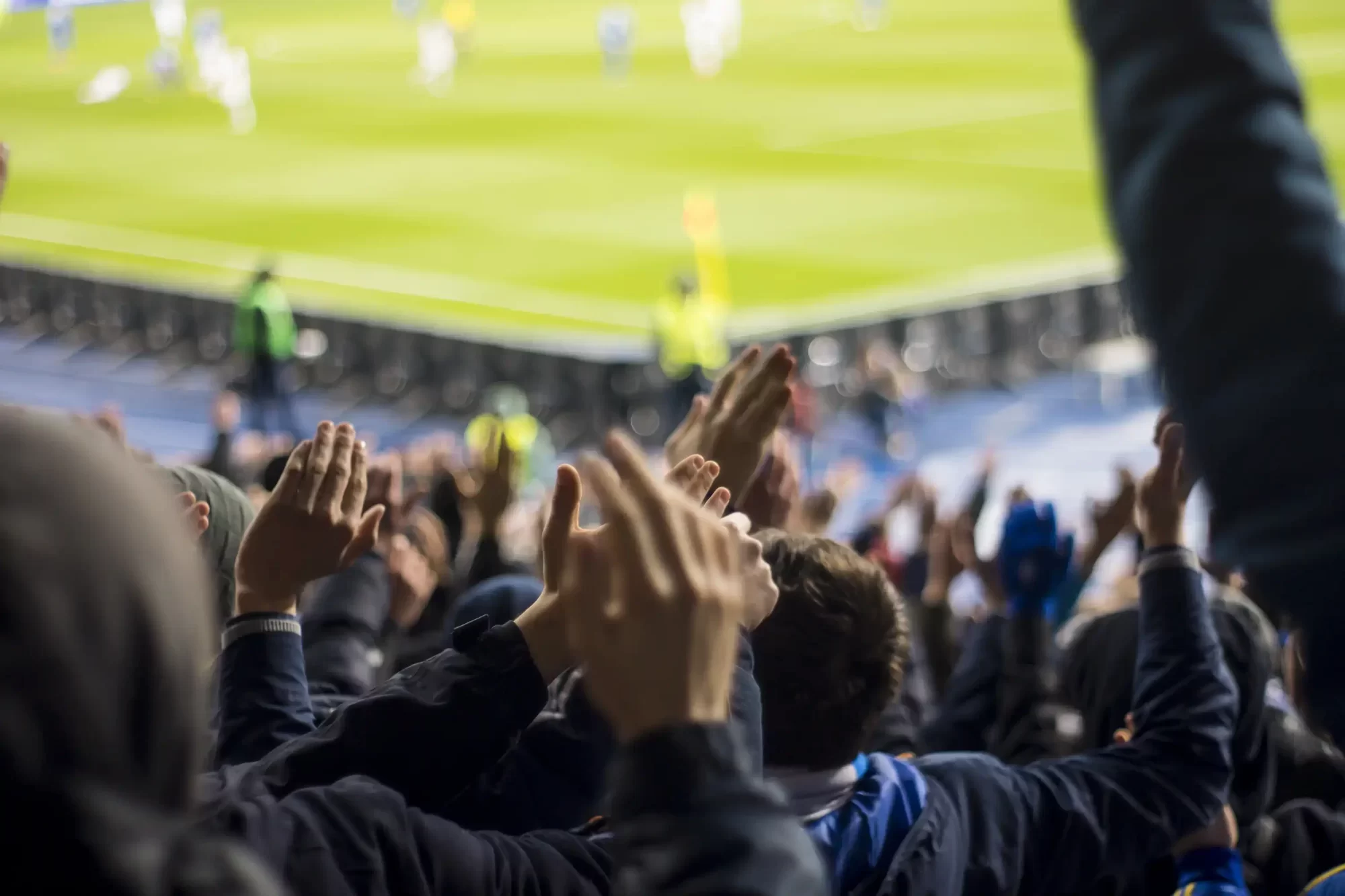 Spettatori applaudono durante una partita di calcio in uno stadio.